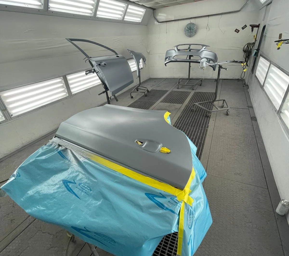 Vehicle panels being refinished inside the AE Collision paint booth